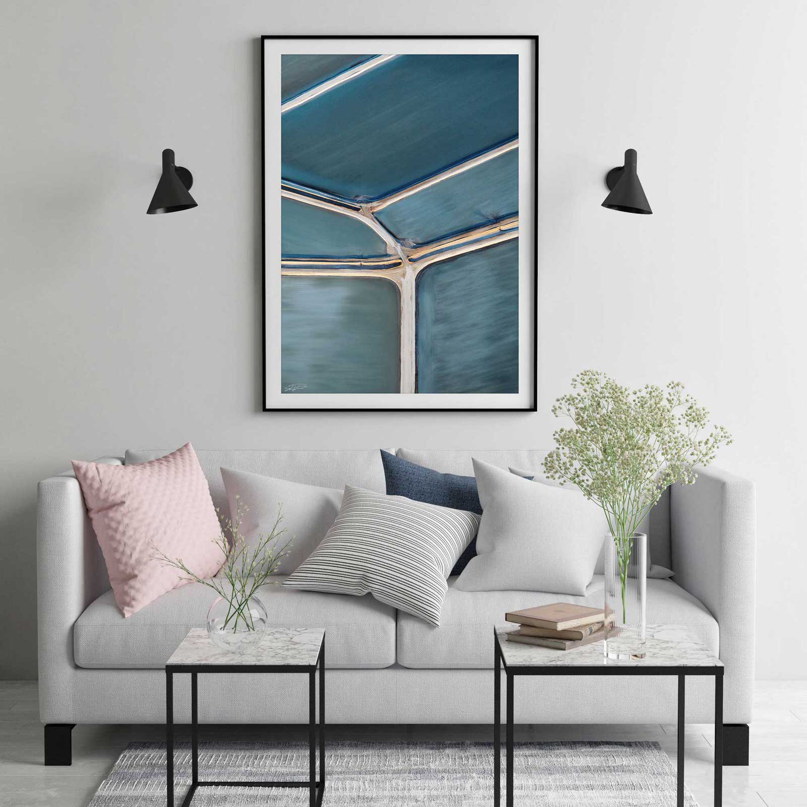 Abstract aerial print in black frame hanging on wall with couch