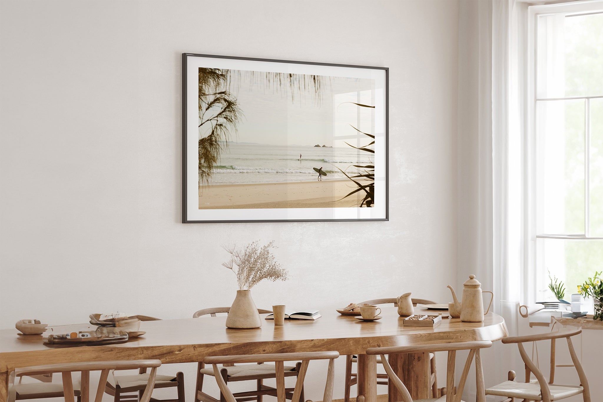 Byron Bay pastel surf print shown framed in black above an oak table.
