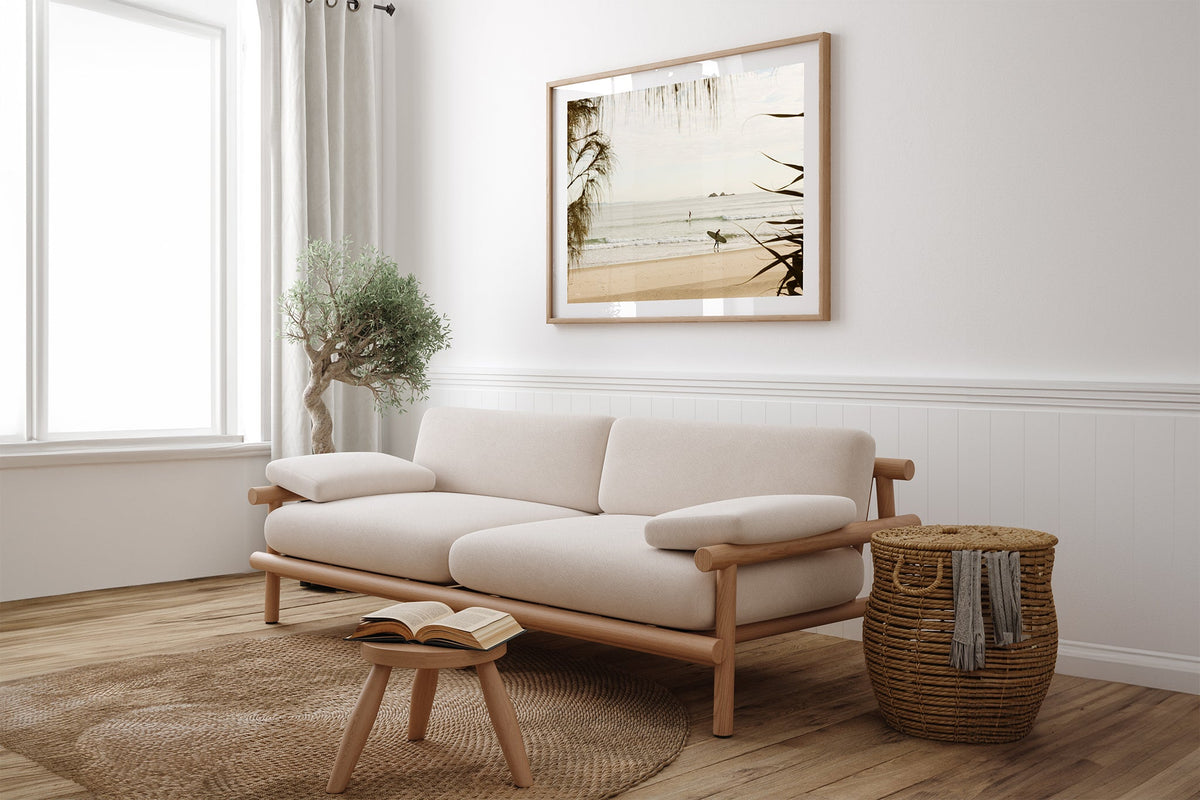 Byron Bay pastel surf print shown framed in oak above a linen couch.
