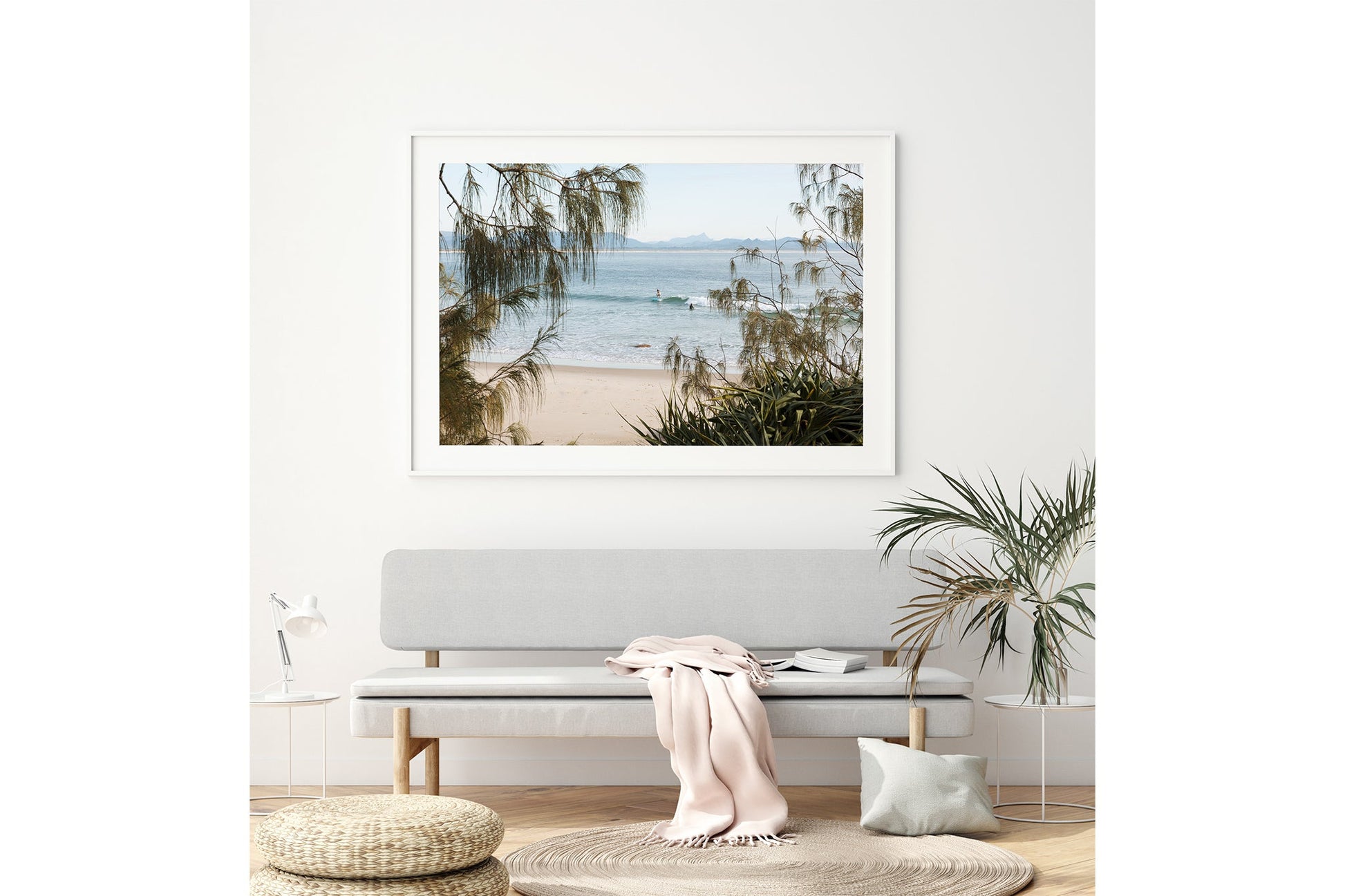 Byron Bay coastal print shown framed in white above a bench seat.