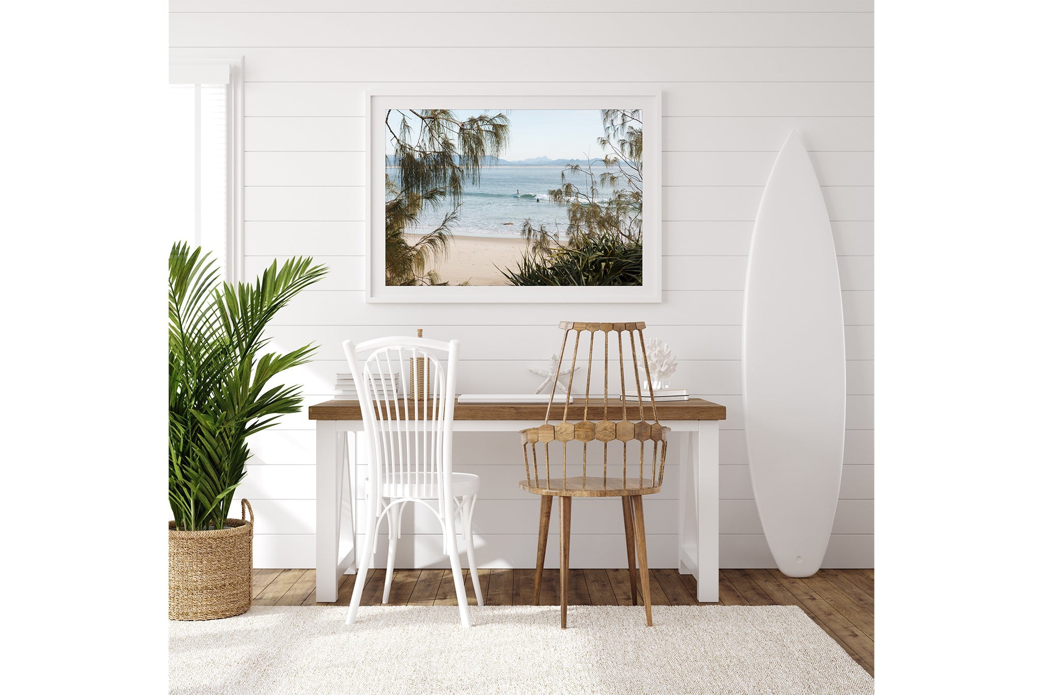 Byron Bay coastal print shown framed in white beside a surfboard in a coastal room.