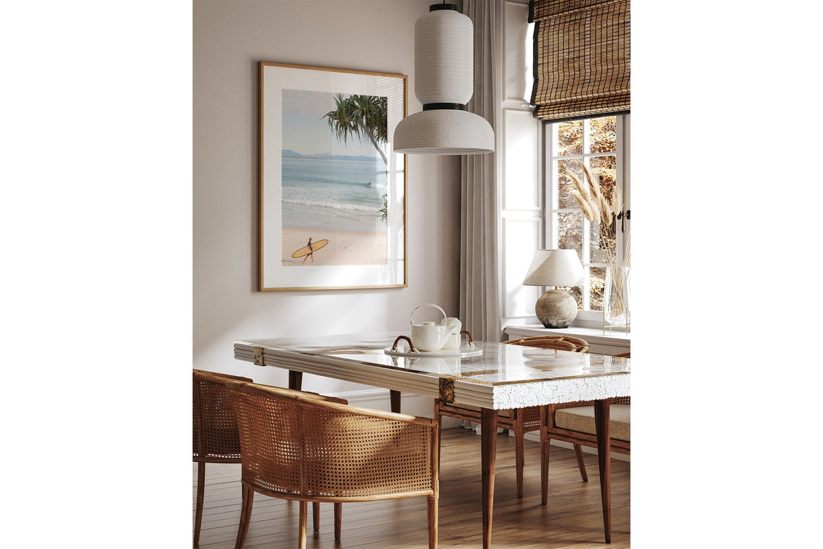 Yellow longboard Byron Bay print shown framed in oak above a dining table.