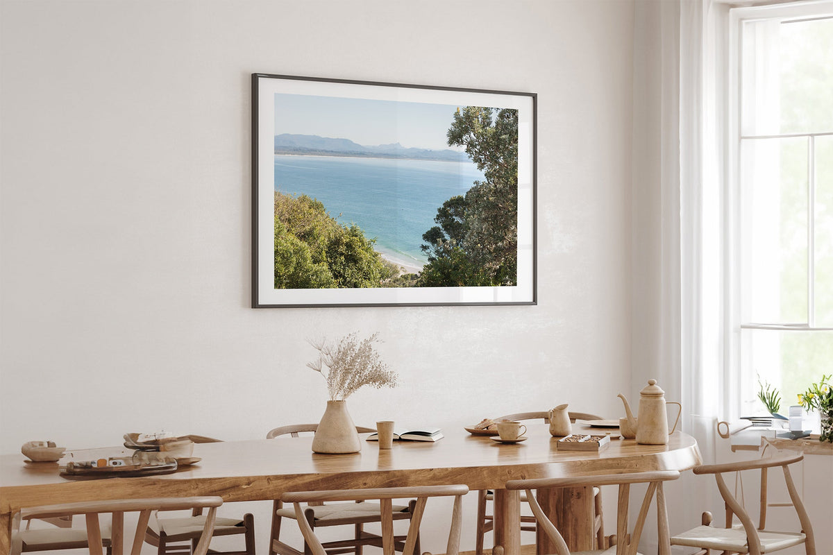Byron Bay lookout print shown framed in black above an oak table.