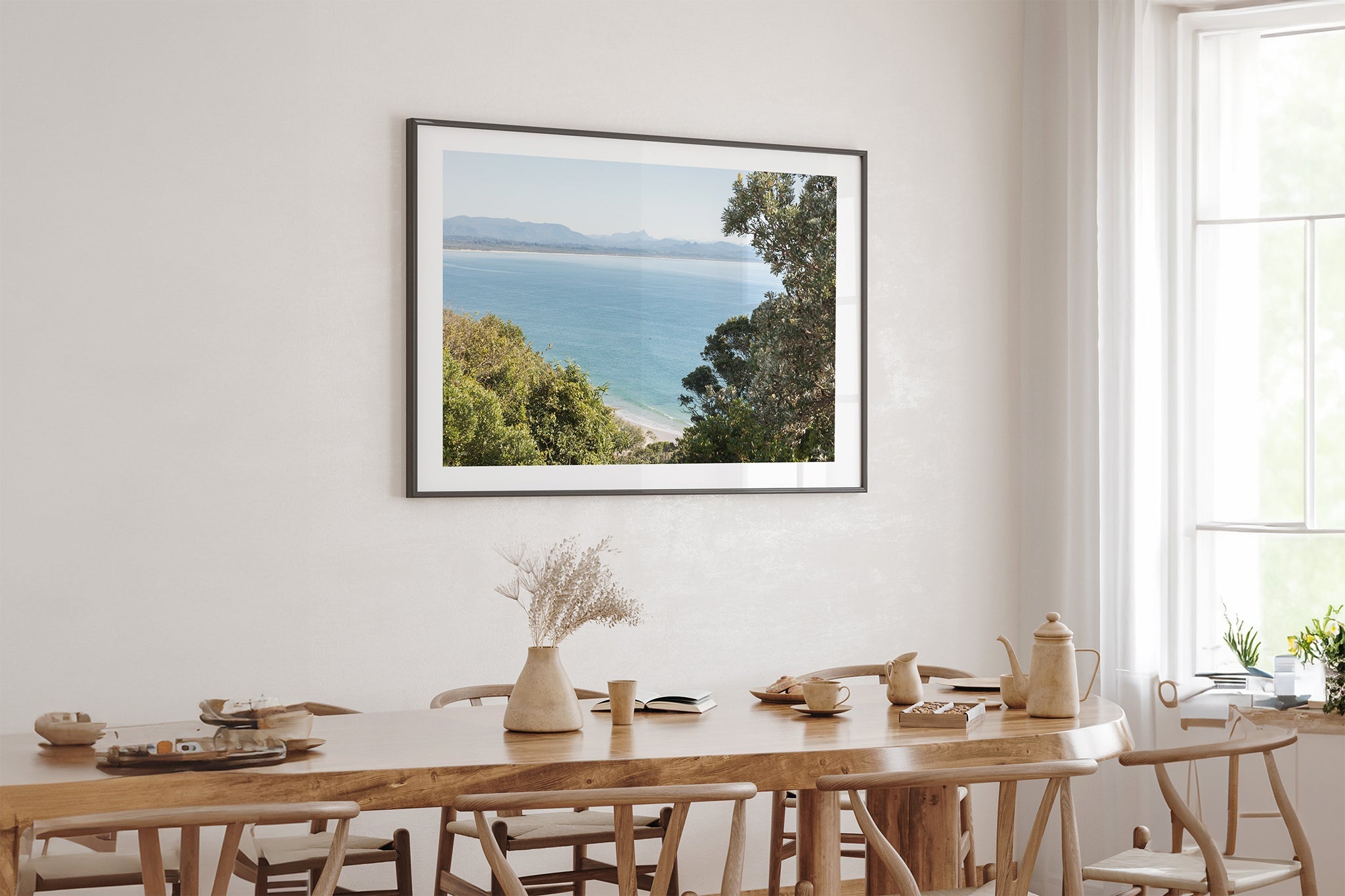 Byron Bay lookout print shown framed in black above an oak table.