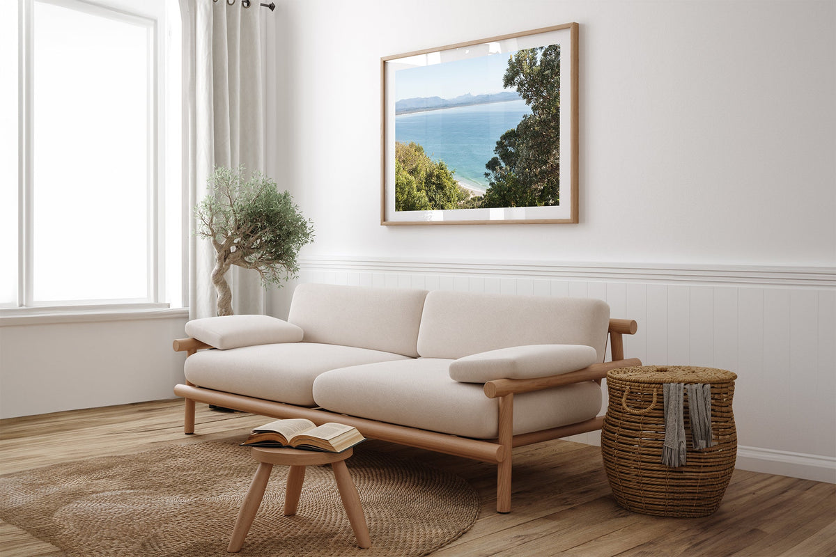 Byron Bay lookout print shown framed in oak above a linen couch.