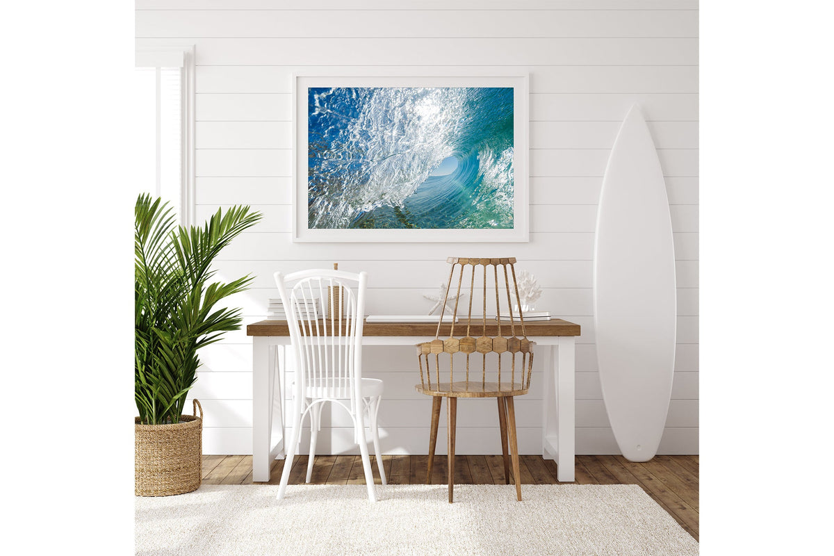 Glass Tunnel print shown framed in white on a white shiplap wall with a surfboard leaning beside a desk.