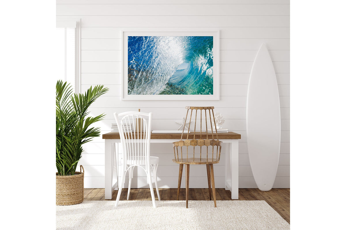 Blue Chamber print shown framed in white on a white shiplap wall with a surfboard leaning beside a desk.