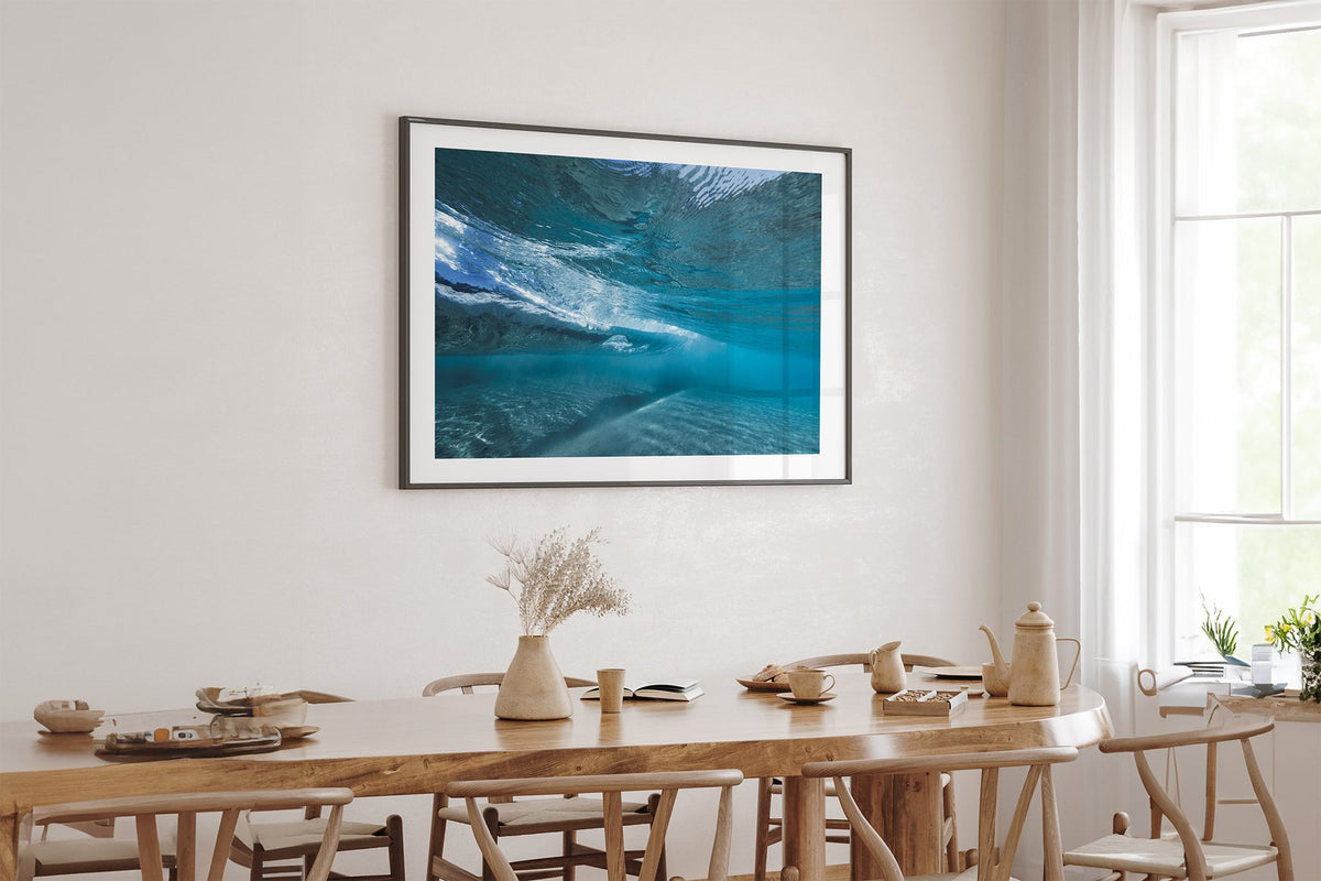 Quiet Shallows print shown framed in black above an oak table.