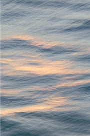 Soft peach and cream light drifting across grey blue rippled water, a gentle slow shutter abstract wall print.