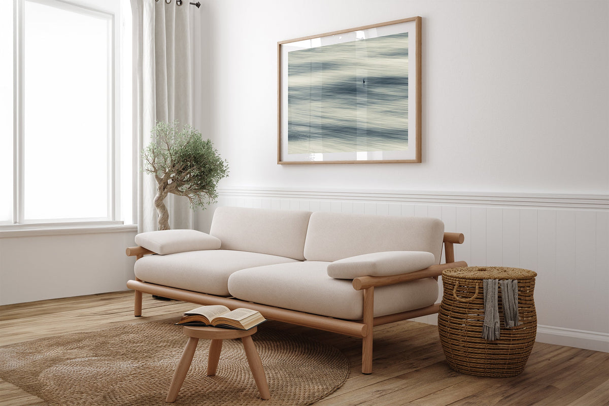 Lone Gull print shown framed in oak above a linen couch.