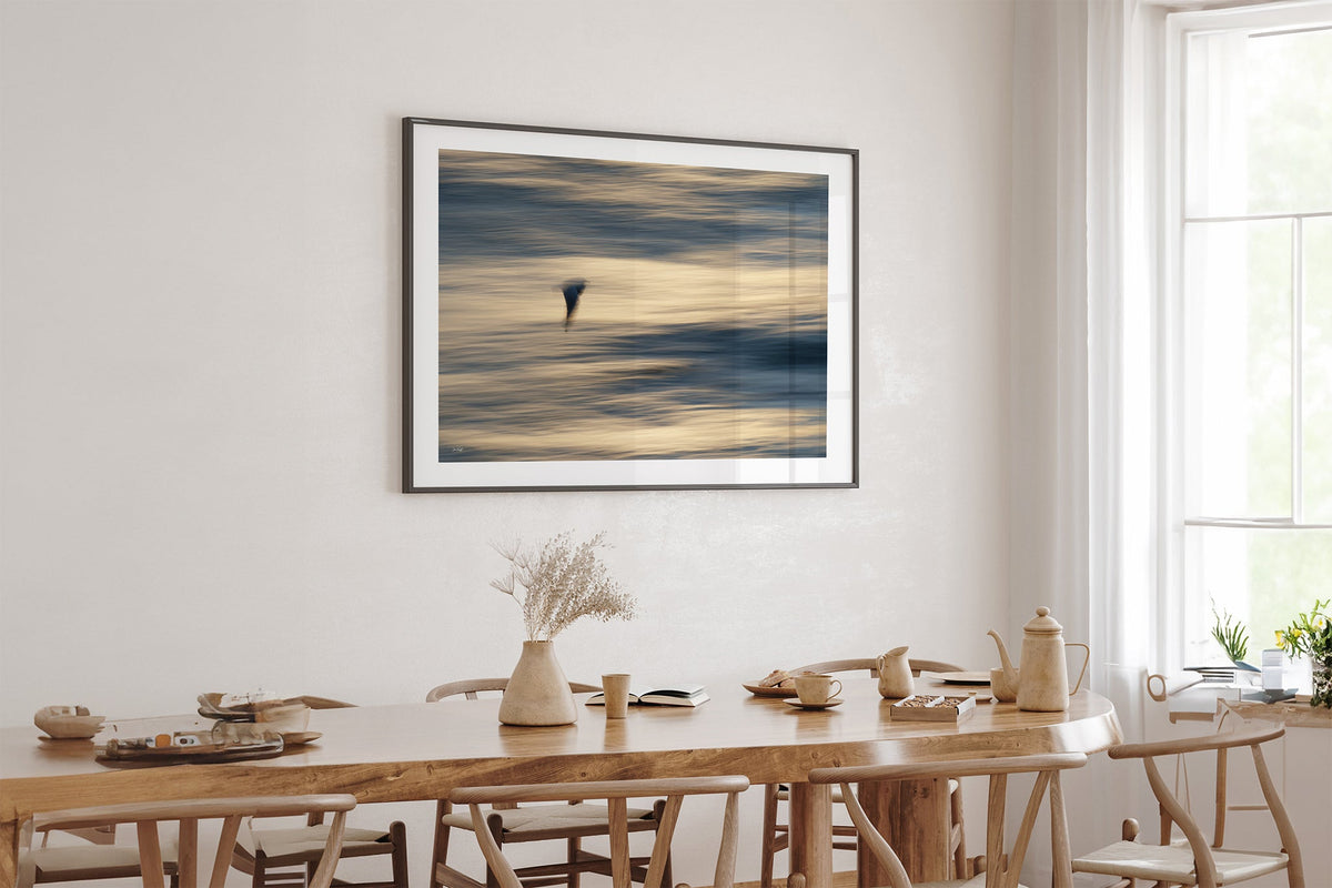 Gliding Gull print shown framed in black above an oak table.