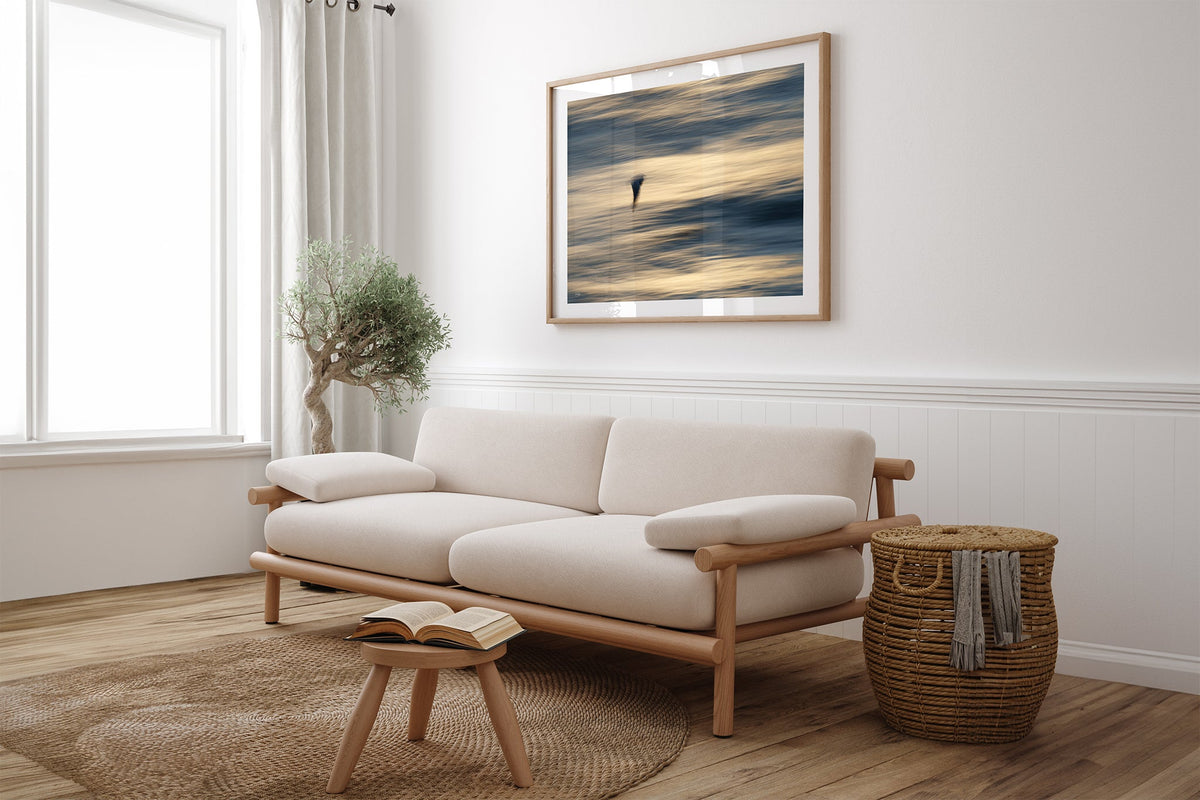 Gliding Gull print shown framed in oak above a linen couch.