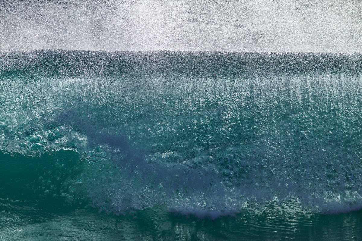A wave face in teal and jade water with a veil of fine white spray across the top of the frame, an abstract ocean wall print.