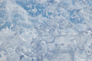 Ribbons and droplets of white sea spray frozen mid-air against a pale blue background, an abstract water wall print.