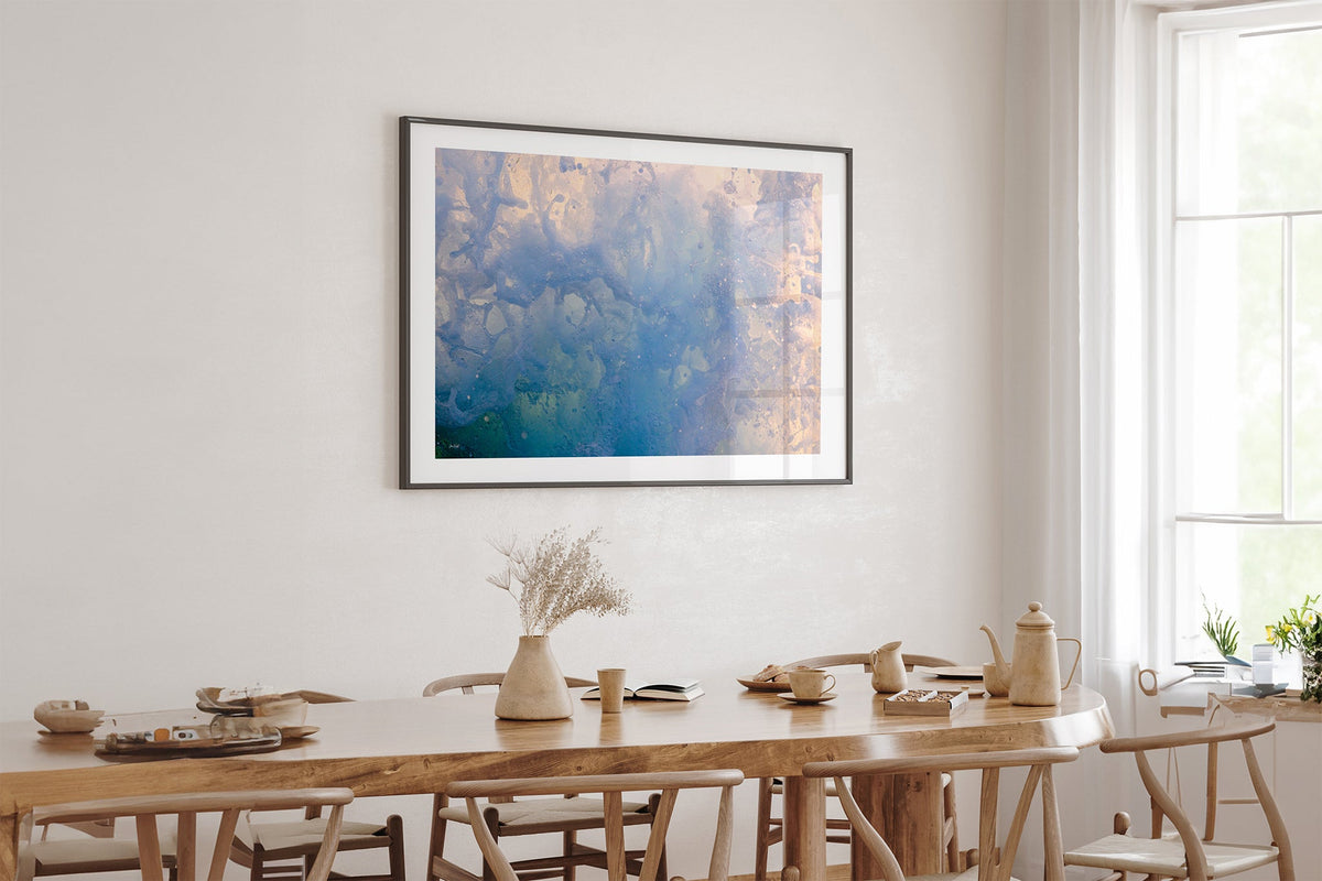 Coral Marble print shown framed in black above an oak table.