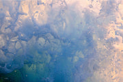Marbled sea foam in blue, green and slate with a soft peach glow on the right side, an abstract ocean wall print.