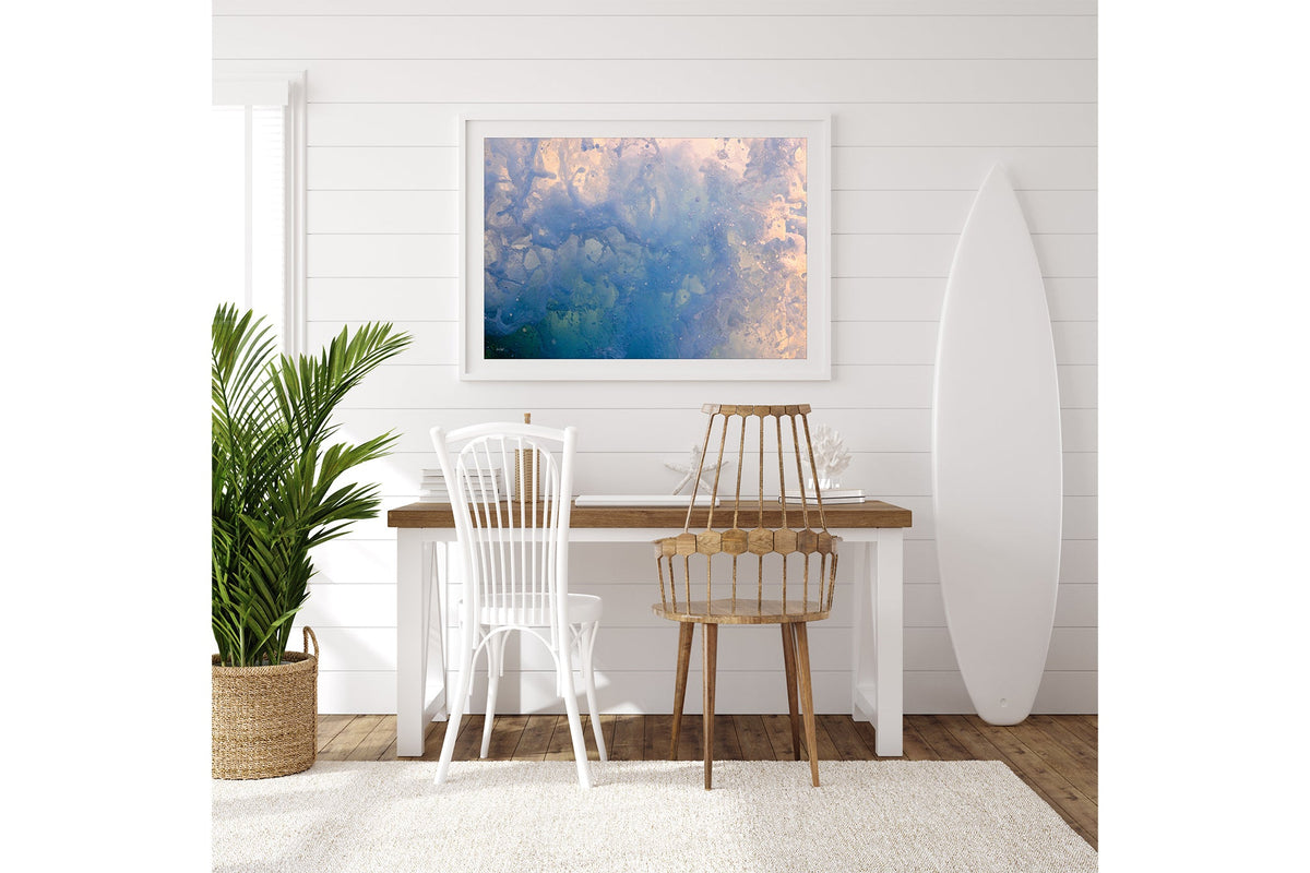 Coral Marble print shown framed in white on a white shiplap wall with a surfboard leaning beside a desk.
