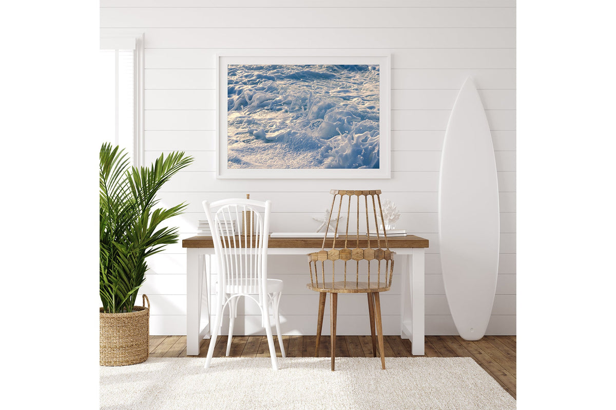 Frost Foam print shown framed in white on a white shiplap wall with a surfboard leaning beside a desk.