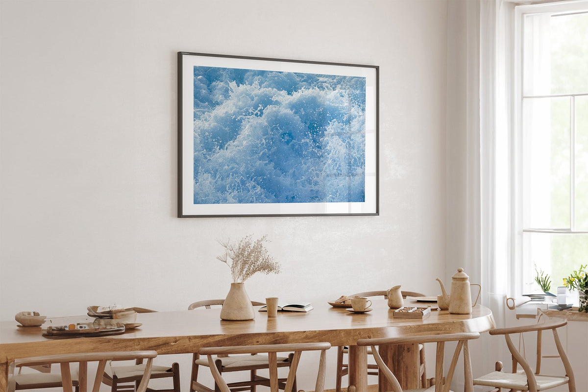 Cobalt Chaos print shown framed in black above an oak table.