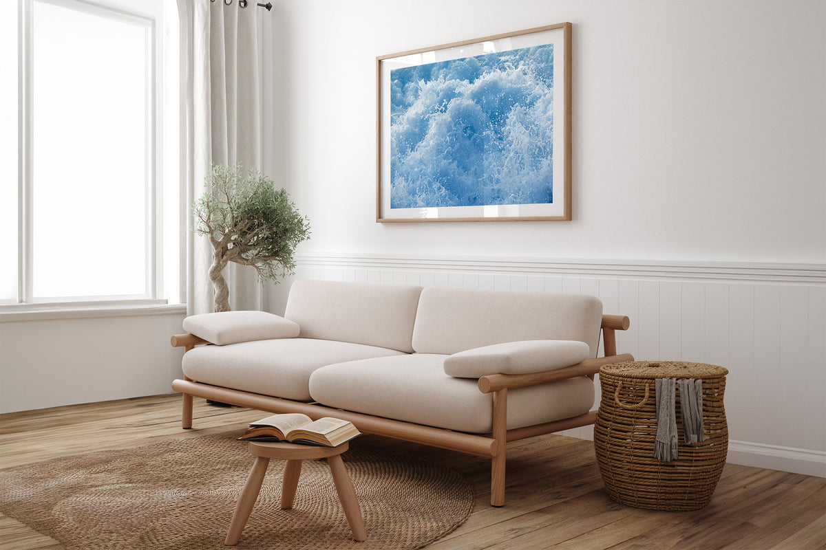 Cobalt Chaos print shown framed in oak above a linen couch.
