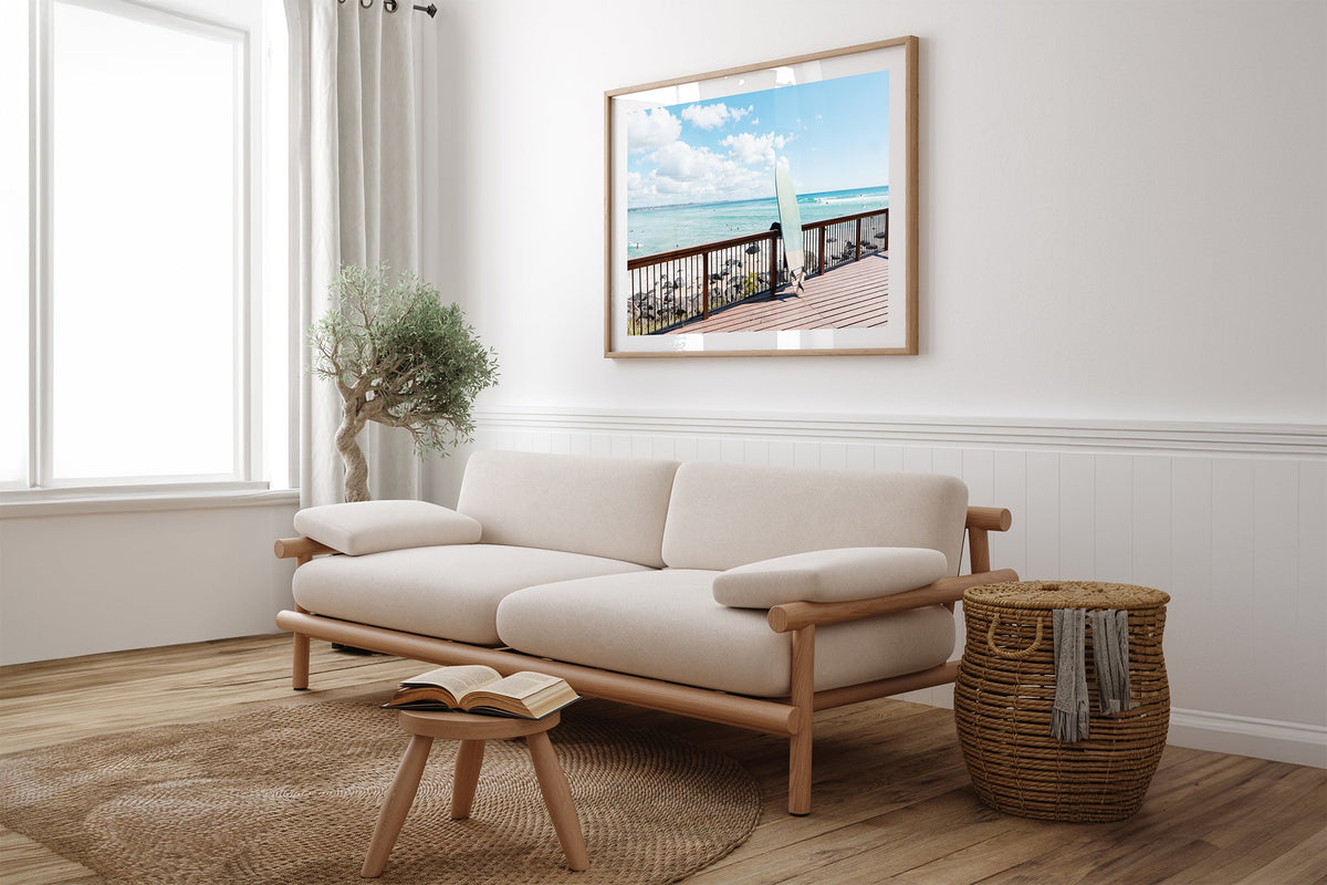 Boardwalk Break print shown framed in oak above a linen couch.