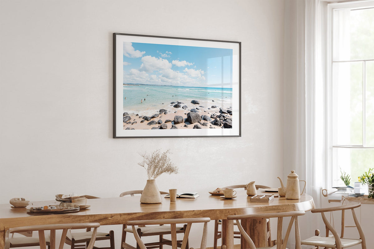 Rock Pool Shallows print shown framed in black above an oak table.
