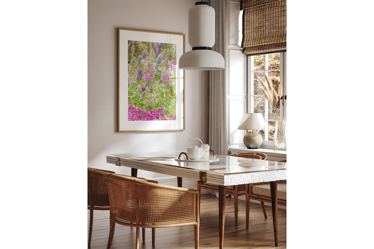 Cottage garden floral print shown framed in oak above a dining table.