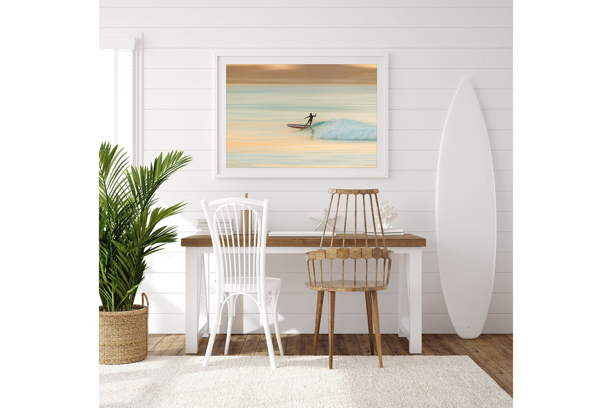Longboard surfer print shown framed in a room with a surfboard.