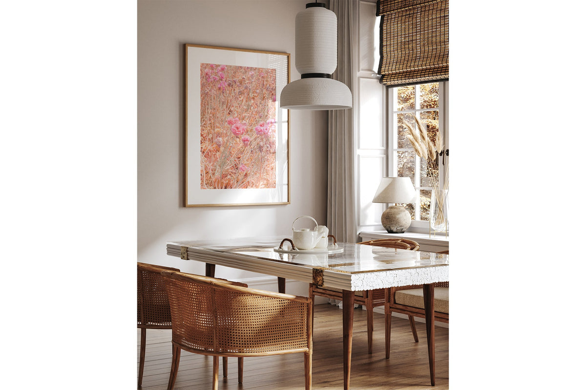 Faded ranunculus print shown framed in oak above a dining table.