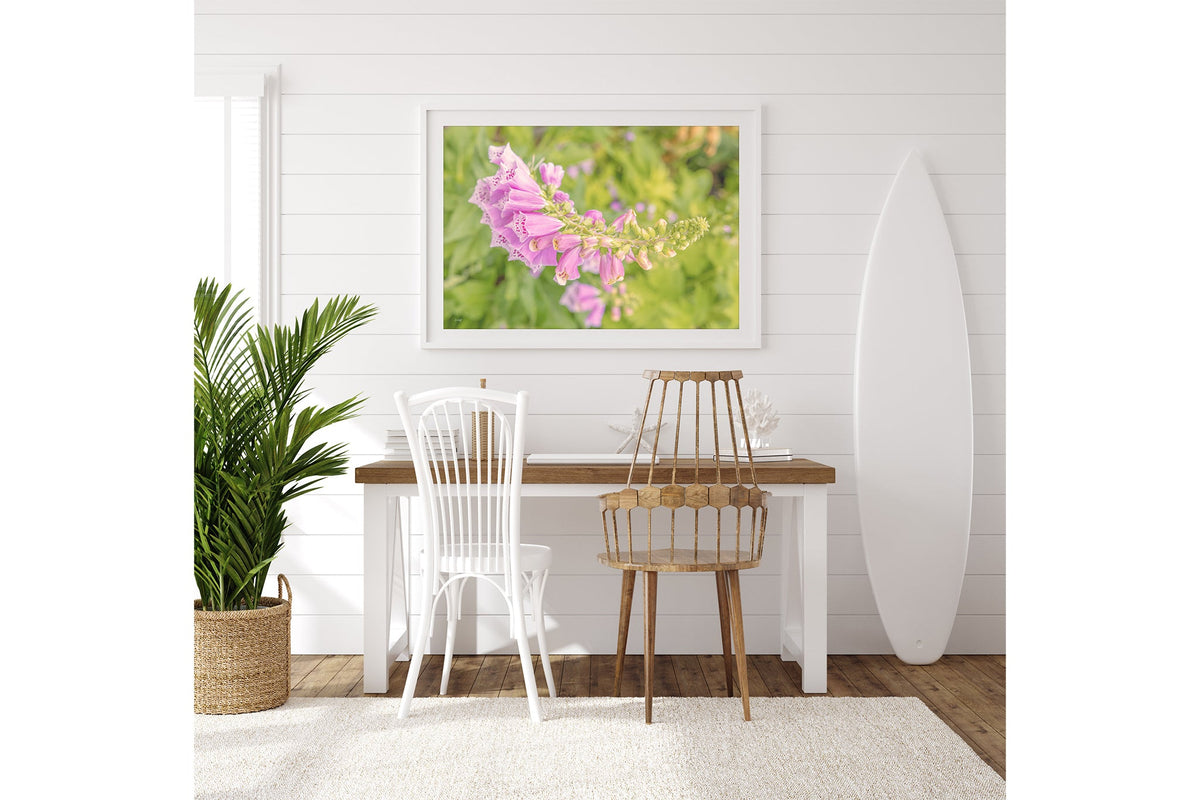 Arching foxglove print shown framed in white on a white shiplap wall beside a desk.