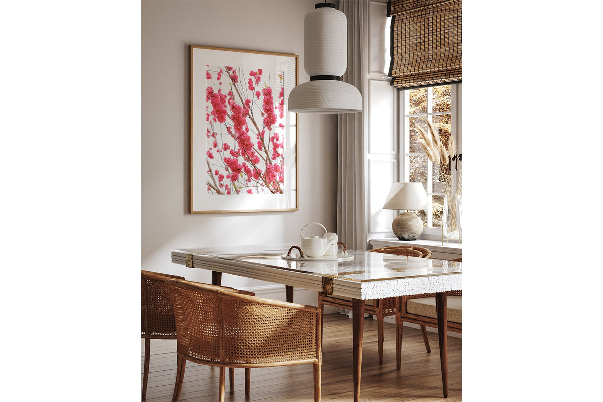 Crimson blossom print shown framed in oak above a dining table.