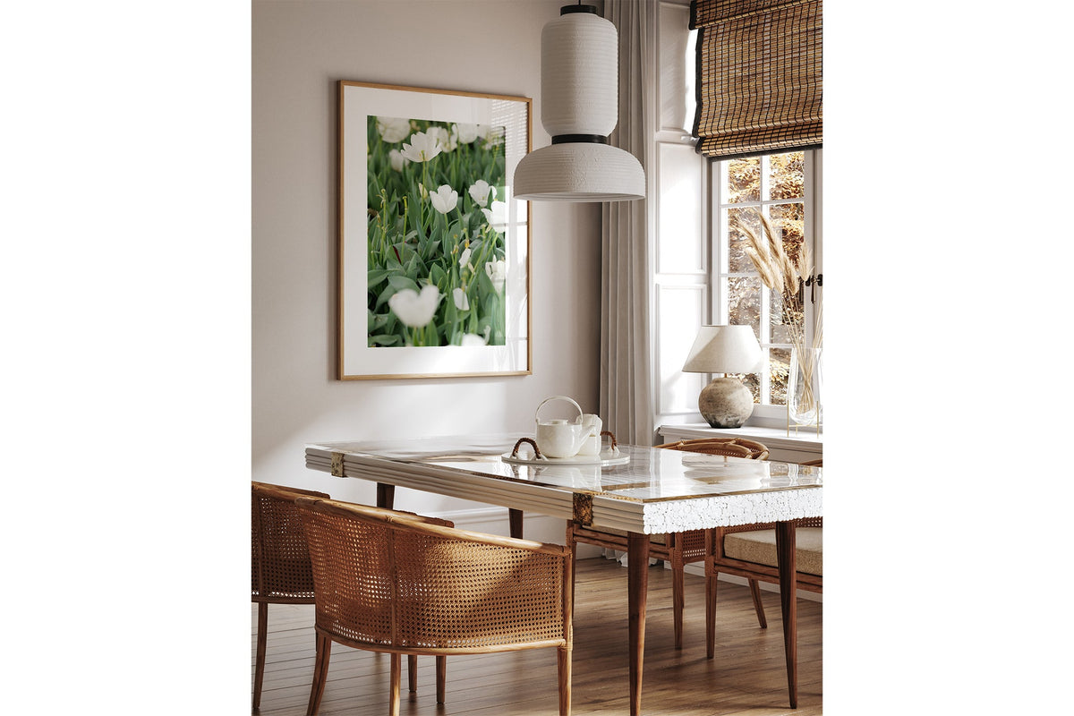 White tulips print shown framed in oak above a dining table.