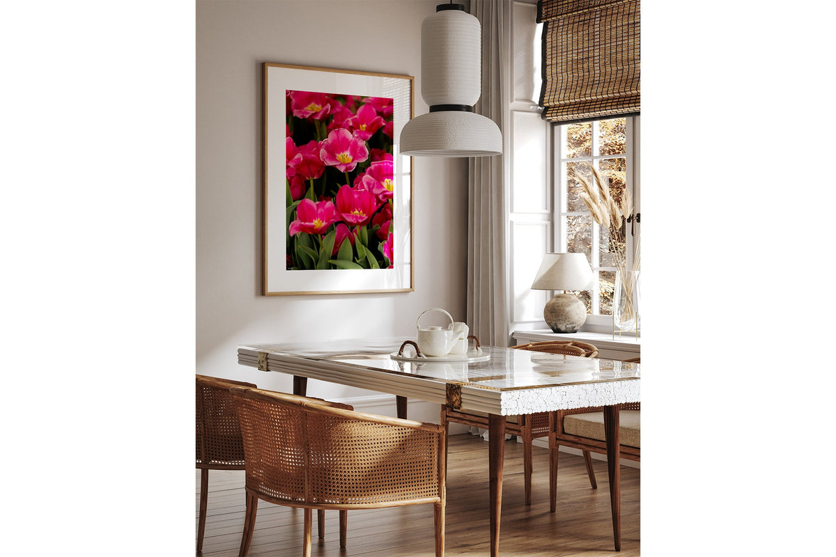 Magenta tulip print shown framed in oak above a dining table.