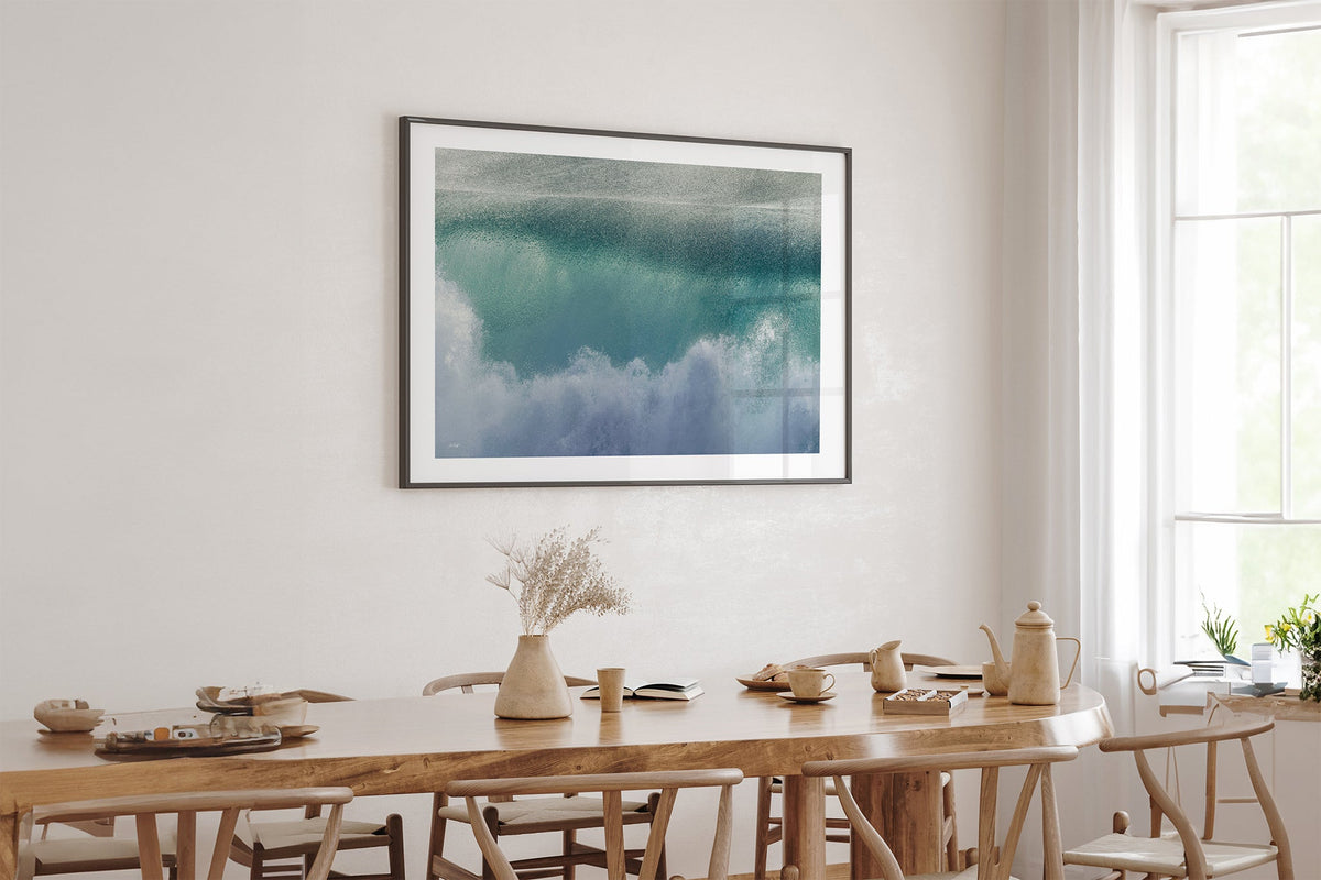 Aqua wave print shown framed in black above an oak table.