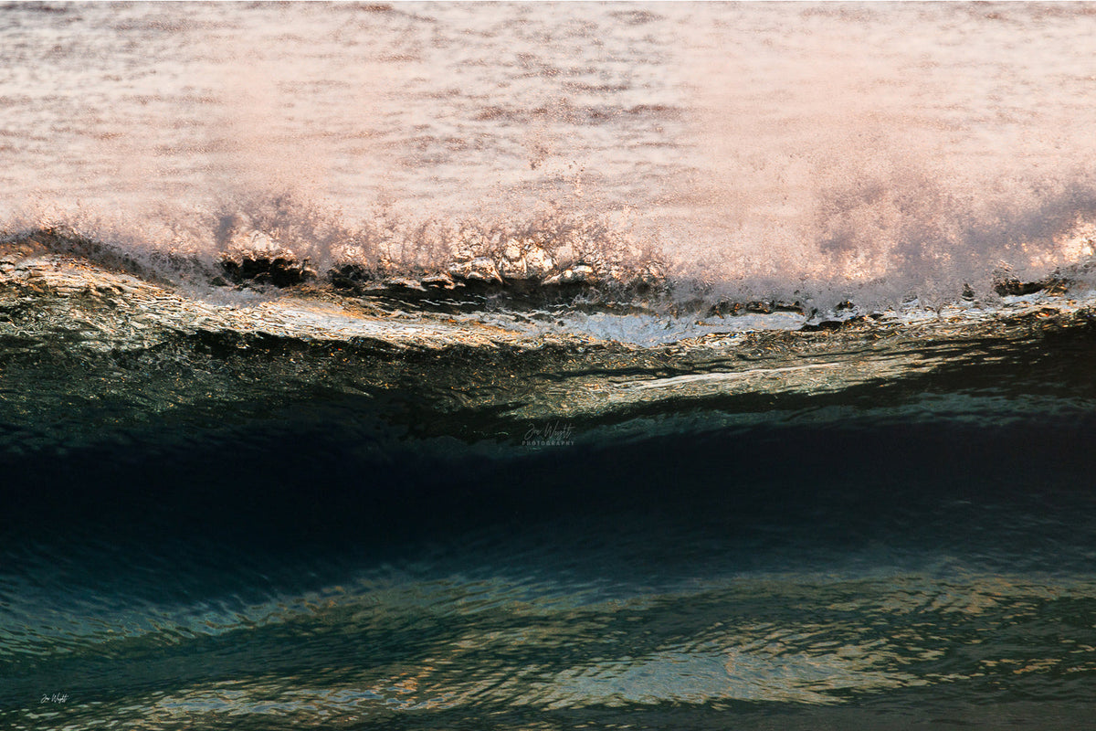 A band of rose pink foam across the top of a dark teal wave face with warm gold glints, an abstract ocean wall print.