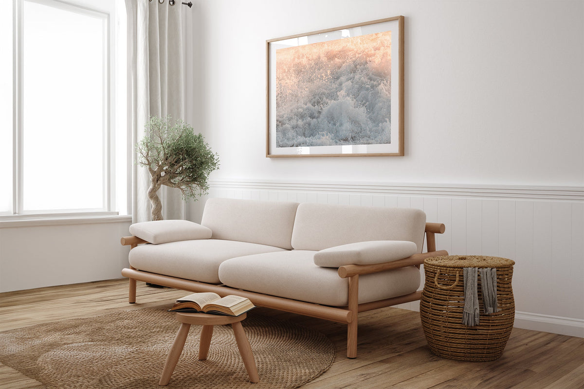 Peach Spray print shown framed in oak above a linen couch.