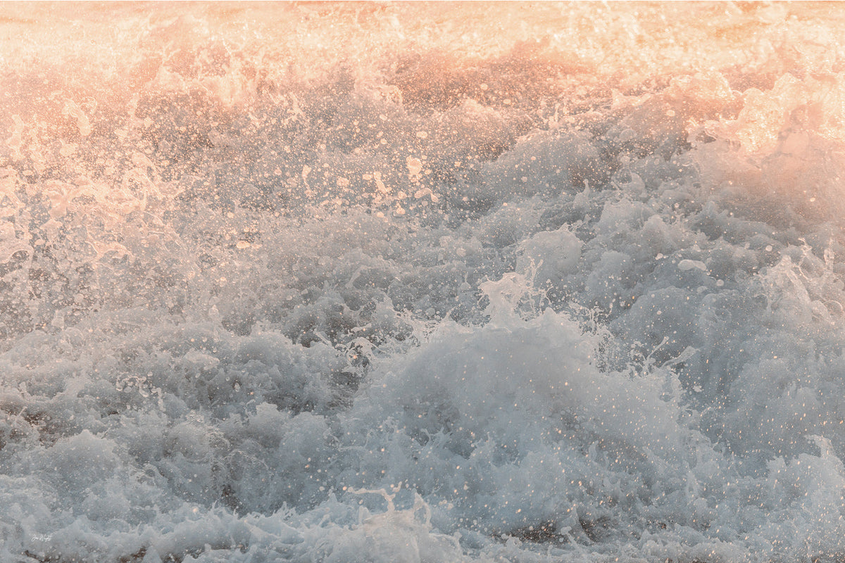Peach and pink light across churning sea spray fading to soft grey and white foam with fine droplets, an abstract ocean wall print.