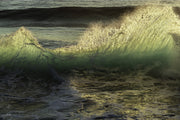 A small wave glowing emerald green and gold as low sun backlights a fan of spray over dark glassy water, an ocean wall print.