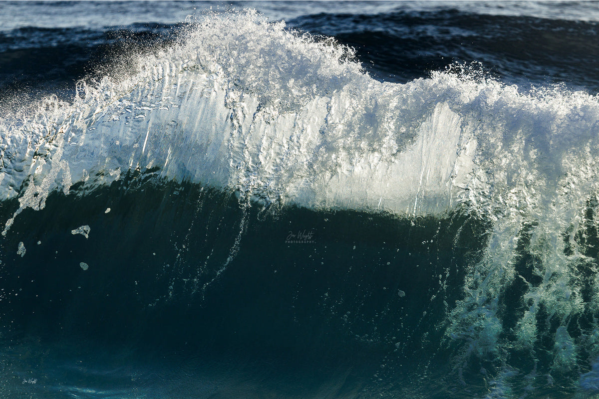 A glassy white wave crest with fine ridges over a deep navy and teal wave face, a dark ocean wall print.
