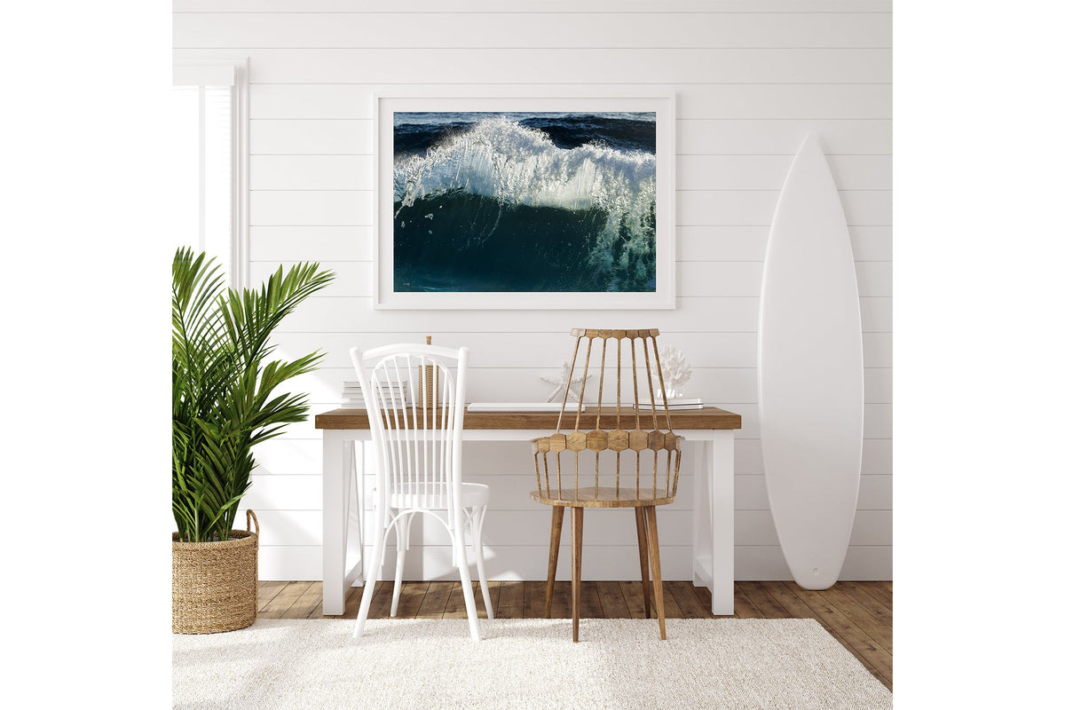 Glacier Crest print shown framed in white on a white shiplap wall with a surfboard leaning beside a desk.