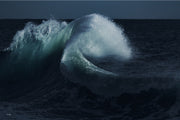 A teal and green wave curling over with a plume of white spray against near black navy water and sky, a moody ocean wall print.