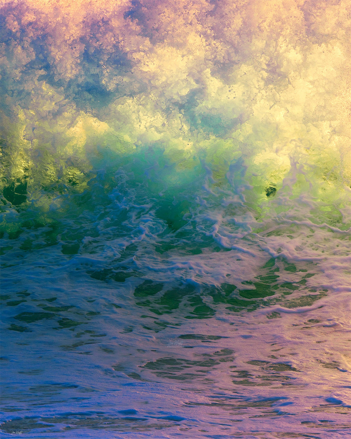 Pastel yellow and green spray above blue, pink and violet churning water with a smiling face in the foam, a colourful abstract ocean wall print.