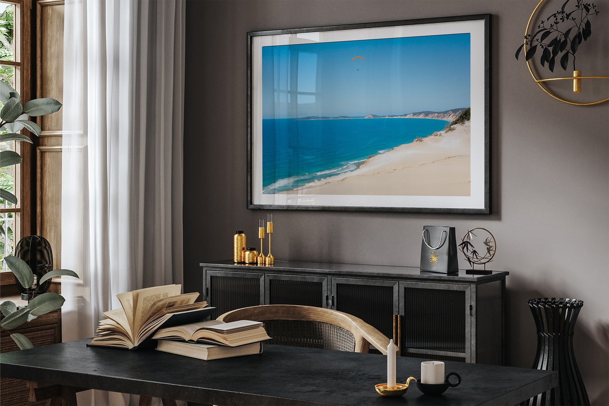 Rainbow Beach paraglider print shown framed in black above a sideboard in a dark toned room.