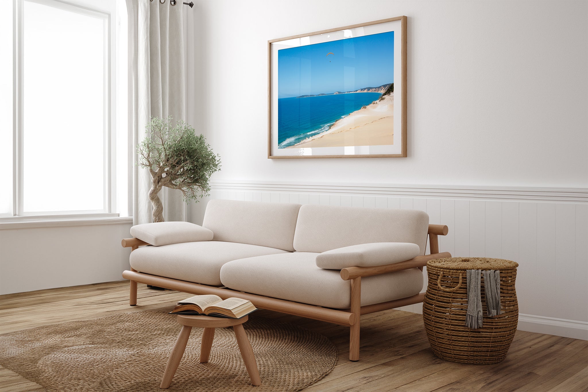 Rainbow Beach paraglider print shown framed in oak above a couch.