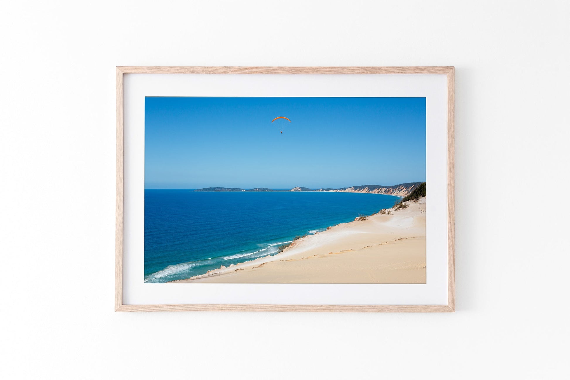 Rainbow Beach paraglider print shown framed in oak.