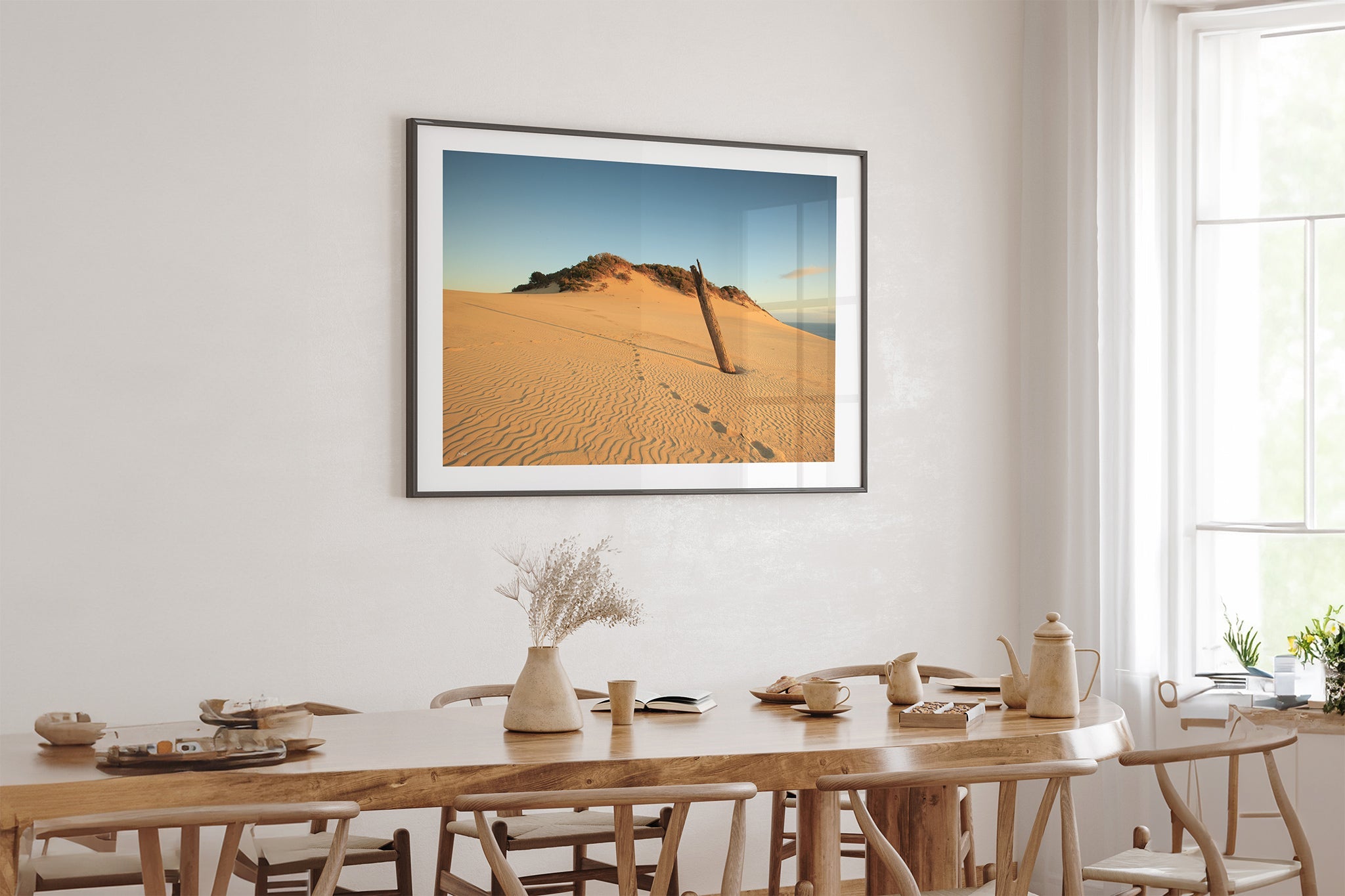 Rainbow Beach dune print shown framed in black above an oak dining table.