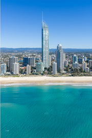 Aerial view of Q1 Tower rising above the Surfers Paradise skyline, with pale sand and turquoise water below.