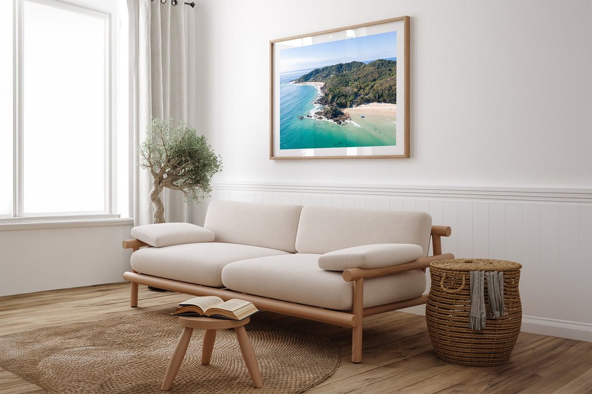 Cape Byron aerial print shown framed in oak above a linen couch.