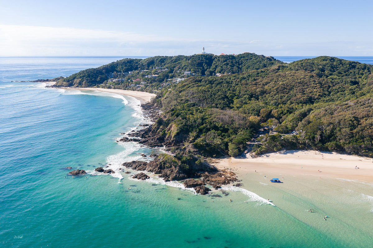 Aerial over Cape Byron with the lighthouse on the headland, turquoise water wrapping The Pass and Wategos Beach, an aerial wall print.