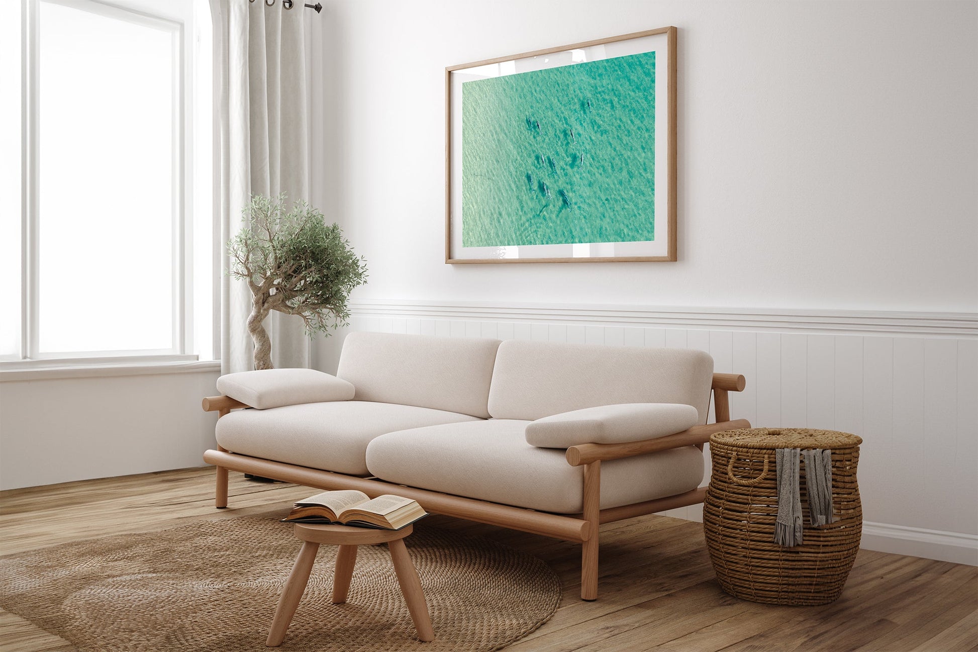 Moreton Bay dolphin pod print shown framed in oak above a linen couch.